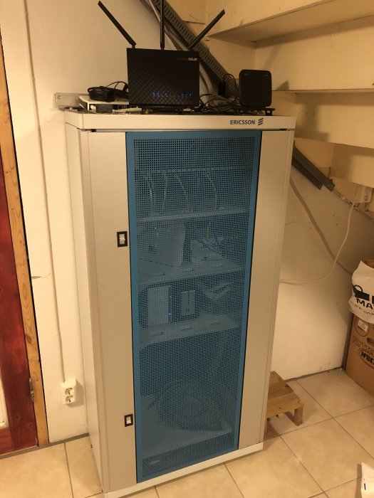 Routrar och nätverksutrustning placerade ovanpå ett blått serverrack i ett förråd.