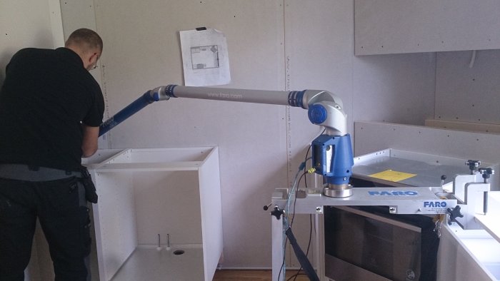 Person använder en 3D-mätarm för att mäta köksskåp inför installation av bänkskiva.