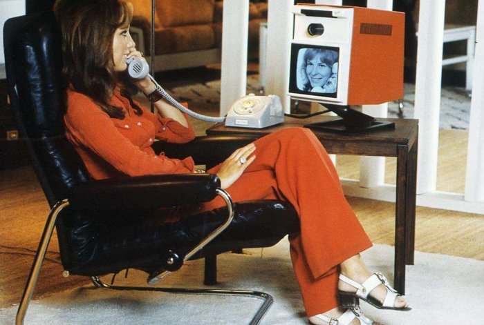 Kvinna i rött samtalar via en telefon med videofunktion från 1971, liknande modern Skype.