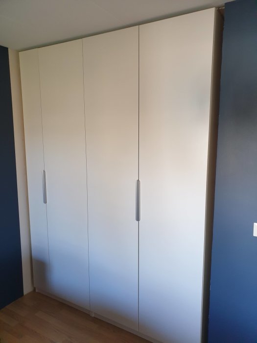 IKEA PAX garderober installerade mot en blå vägg, med synlig mellanrum på sidan för passbit.