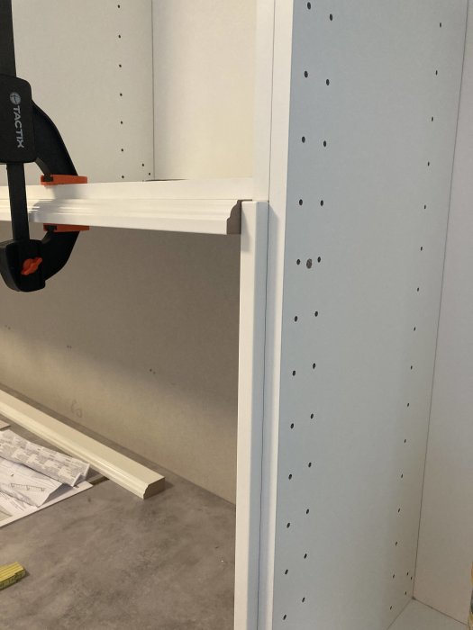 Vit dekorlist som inte möter täcksida korrekt vid ett köksskåps kant, visande problemområdet.