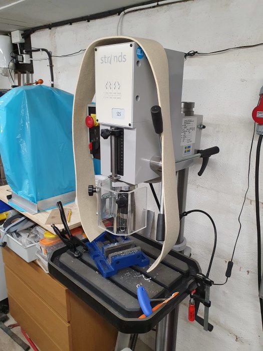 Borrpress i verkstad med maskinfilt för värmeisolering monterad runt maskinen.