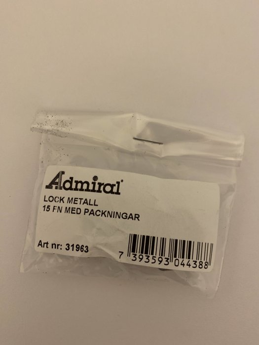 Plastförpackning från Admiral med texten "LOCK METALL 15 FÖRPACKNINGAR" och artikelnummer visande.