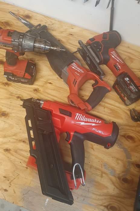 Verktyg från Milwaukee inklusive en ny spikpistol M18 FFN på ett träbord.