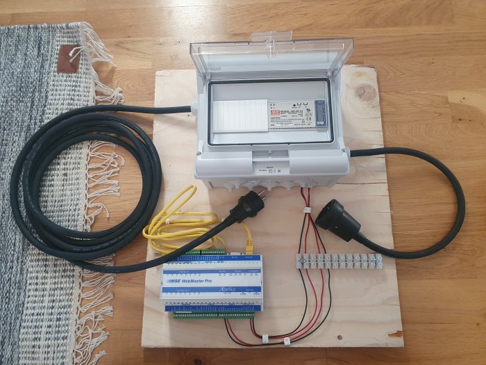 Elutrustning monterad på träplywood inklusive energimätare, kapsling och WebMaster Pro med kablar och kontakter.