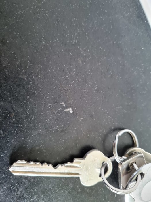 Repa på svart naturstensbänkskiva med nyckelknippa som storleksreferens.