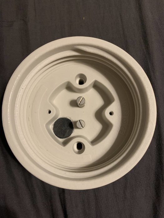 Omonterad Ifö Glob lamparmatur med synlig skruv och förmonterade delar på en textilbakgrund.