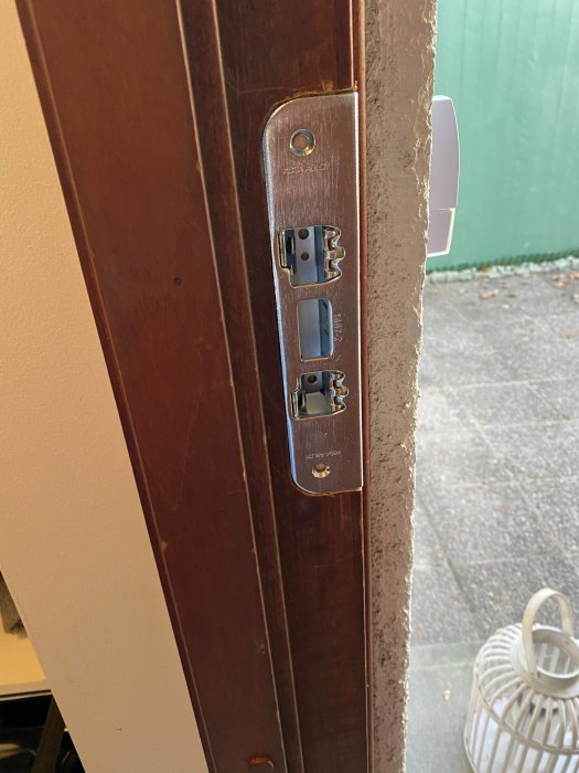 Dörr med nyinstallerat lås, urtagningar syns, gammal ring sticker ut bakom låsplattan.