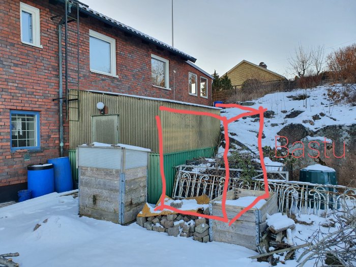 Gammalt trädgårdsförråd vid husvägg med snö och markeringar för planerat nytt förråd och bastuområde.