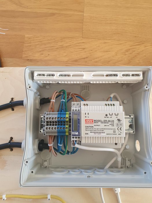Elektrisk kapsling med ordnat kablage där nät- och lågspänning är separerade och säkrade med buntband.