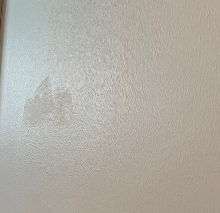 Ommålat område på en vägg där penseldrag syns vid viss vinkel.