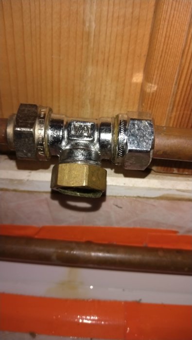 Skadad kopplingsbult på ett vattenrör, med tecken på vattenläckage, som ansluter till en duschblandare.