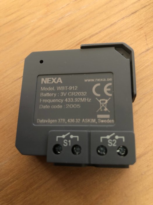 NEXA trådlös sändarmodul WBT-912 med knapparna S1 och S2, placerad på ett träbord.