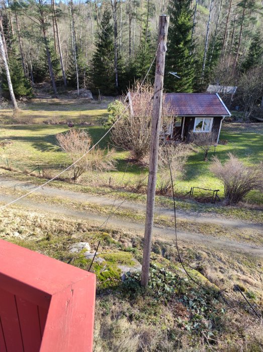 Gammal telefonstolpe i trädgård, potentiell fästpunkt för solsegel nära en altan.