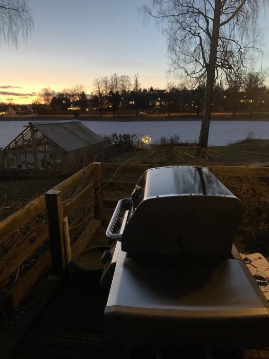 Stängd grill på en terrass med utsikt över en frusen sjö vid skymning.