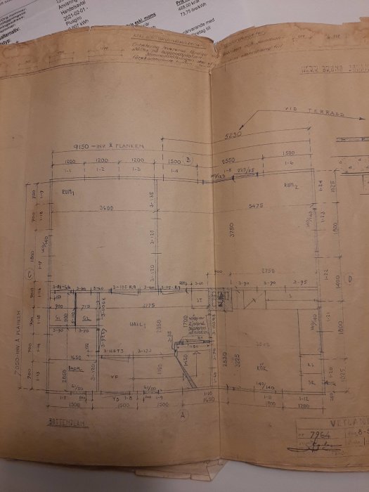 Äldre gulnad arkitektritning av en bottenvåning med handskrivna mått och rum beteckningar som kök och vardagsrum.