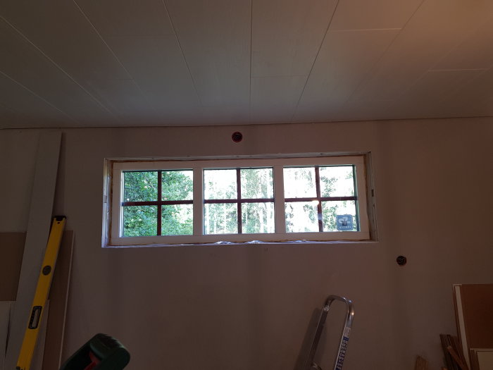 Nylonstegad stege och verktyg i rum under renovering med nyligen installerat fönster.