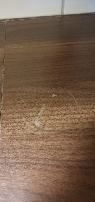 Mörk laminatbänkskiva med vita fläckar och en synlig ringmärke.