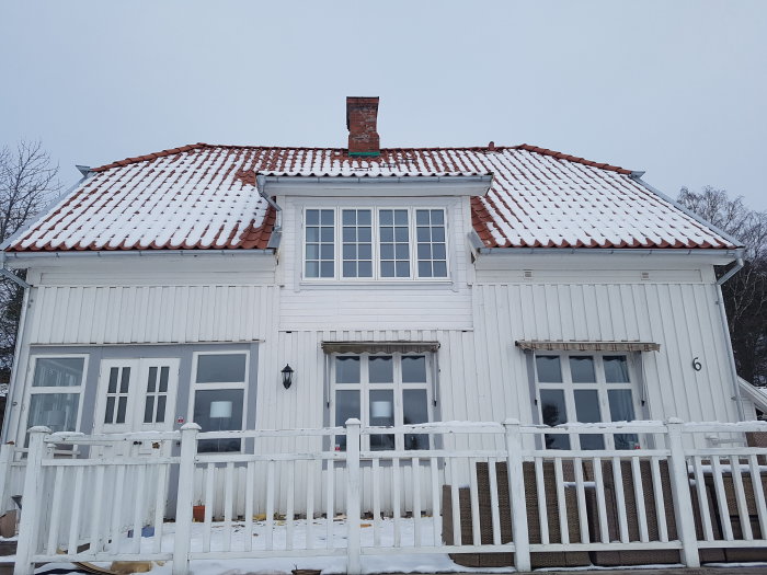 Vitt hus med snötäckt tak och nytt stort fönster som är öppningsbart på sidorna.