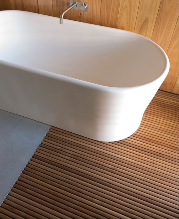 Ett modernt badrum med ett frittstående ovalt badkar, träribbor på golvet och delvis kaklade väggar.