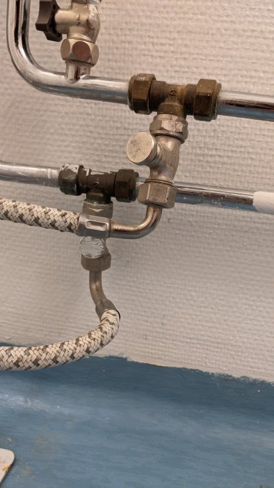 Kopplingar och vattenrör i badrum, potentiell anslutning för ny duschkabin.