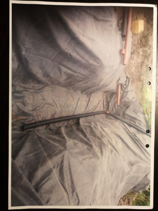 Markbädd med svart rör för vattenavledning och geotextil duken, potentiellt dräneringsproblem.