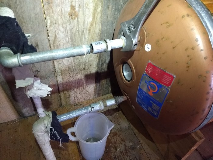 VVS-arbete med kopparledningar och tätning av rörgängor vid en varmvattenberedare.