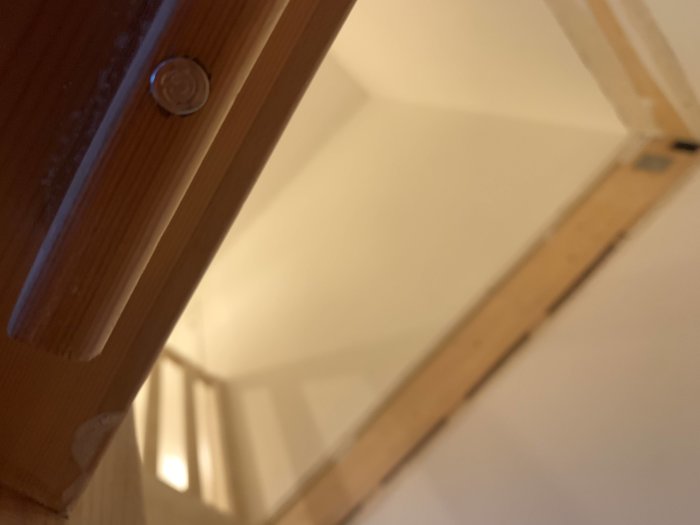 Delvis suddig bild av en furutrappa med en logga som liknar "on/pdf"-symbolen på en lyktkopp under ett trappsteg.