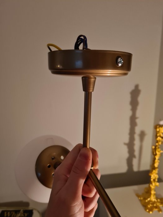 Hand håller en taklampa med sladdar och utan synligt hål för installation mot taket.