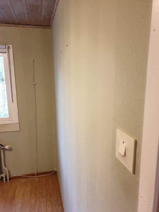 Orenoverat sovrum med trägolv och gröna väggar före renovering.