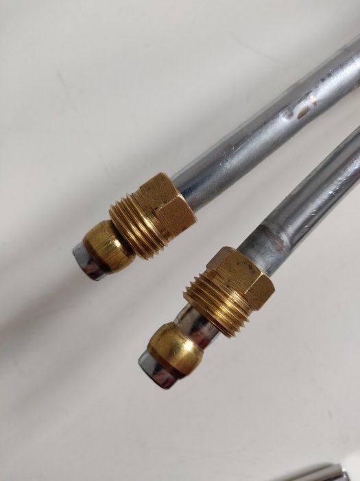 Äldre blandare med 16mm gängade mässingsanslutningar och 10mm rör mot vit bakgrund.