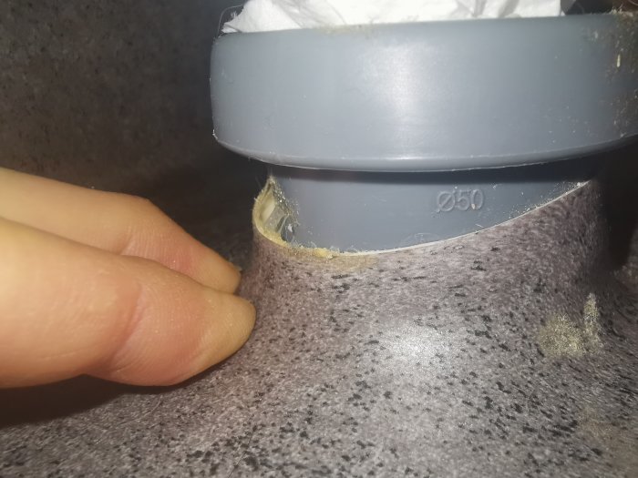 Våtrumsmatta som lossnat runt avloppsrör med synlig bubbla och otillräcklig limning.