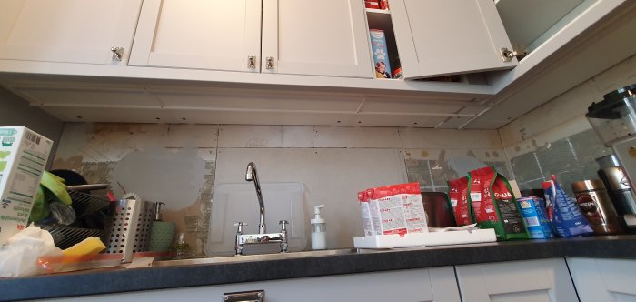 Ikea kök under installation med öppna överskåp och synliga kablar över diskbänken.