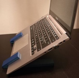 Laptop upphöjd på skrivbordet med blå, 3D-utskrivna ställ för bättre arbetsställning.