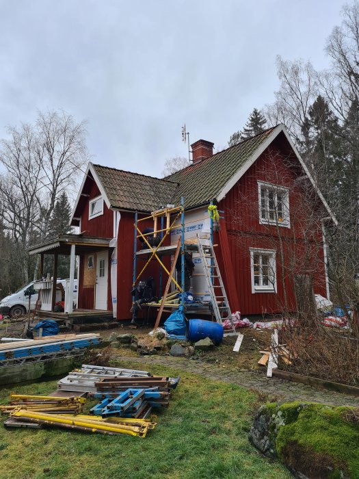 Renovering av ett rött trähus från 1800-talet, med ställningar och byggmaterial runtomkring.