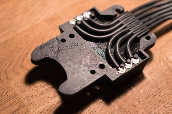 3D-utskrivet svart dammskydd till sänksåg, med tydliga skikt av filament och kablar fästa.