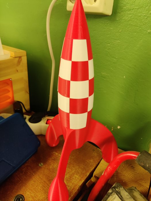 3D-utskriven modell av Tintin-raketen i rött och vitt, placerad på ett arbetsbord.
