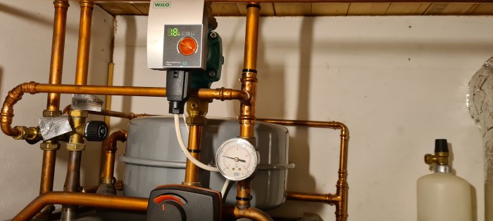 Nytt expansionskärl installerat i värmesystem med kopparledningar, pump och manometer.