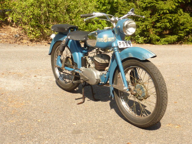 Blå Husqvarna 281 motorcykel från 1953 parkerad på asfalt, känd som "Drömbågen".
