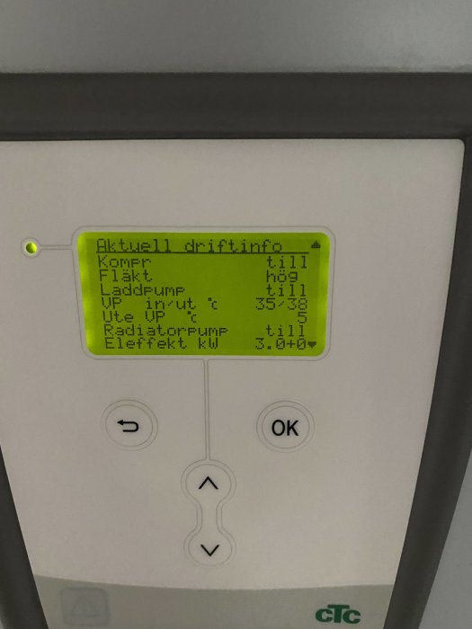 Display på en värmepump med driftinformation, inomhus- och utomhustemperatur samt effektanvändning.