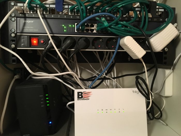 Nätverksutrustning och kablar i en garderob inklusive switchar, router och uttag.