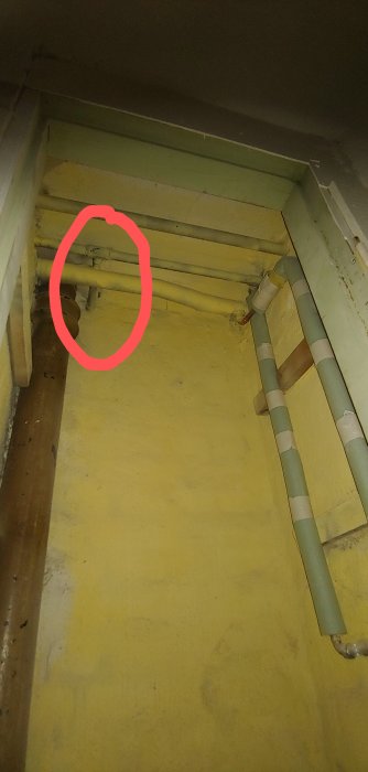 Vy av avloppsrör i en källare markerade för badrumsrenovering, inkluderar äldre rör från 30-talet.