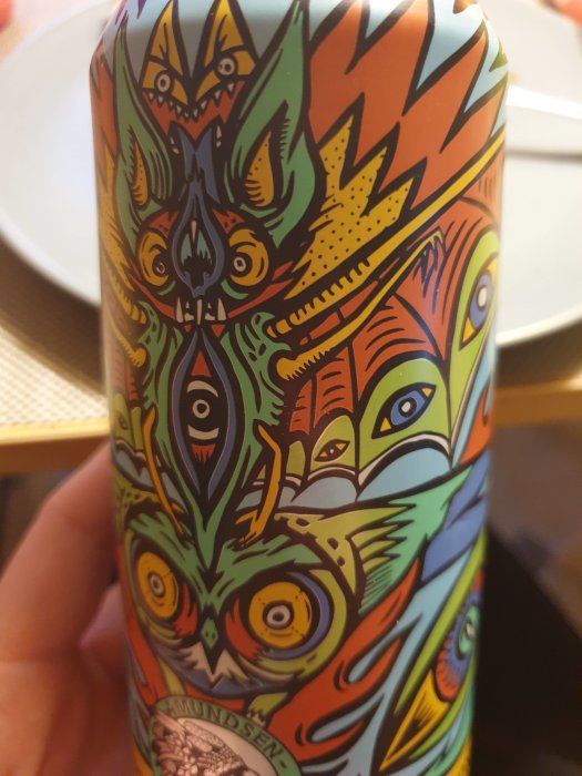 Färgglad och detaljerad illustration med abstrakta mönster och ansikten på en dryckesburk.