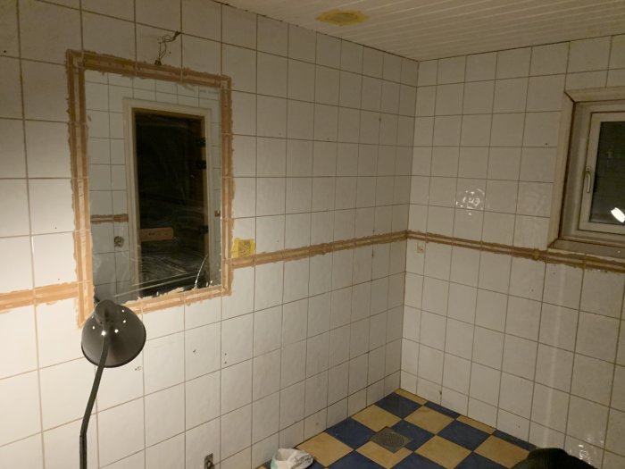 Rum under renovering med väggar delvis fjärlat från kakel och synliga spår av arbetet, tomma på möbler.