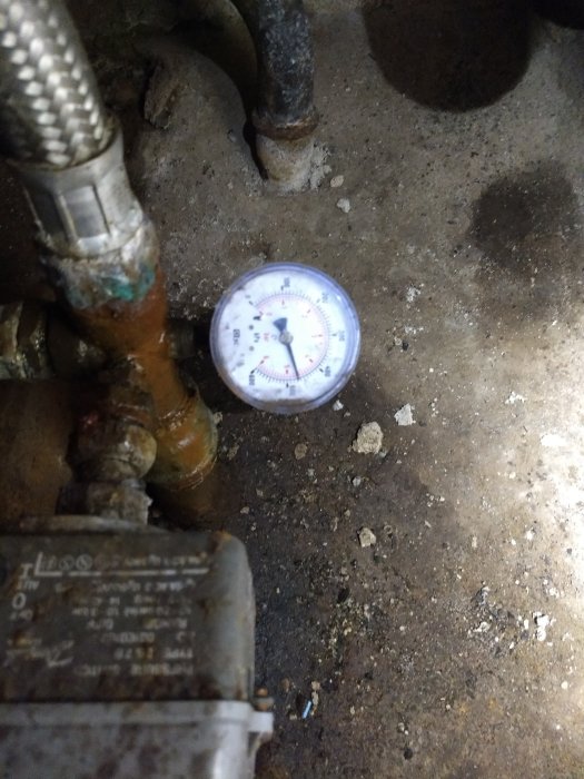 Tryckmätare kopplad till vattenledning och en pump, indikerar stabilt tryck i systemet.