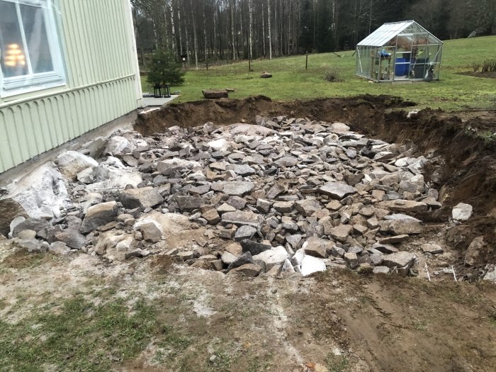 Uppspräckt berg och stenar vid husgrund efter hydraulisk bergspräckning.