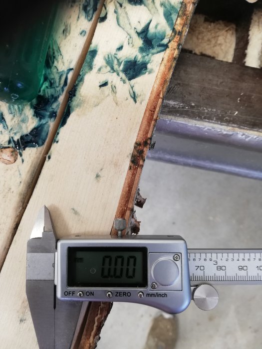 Digital skjutmått visar 0.00 mm mot kant av trästycke och epoxy.