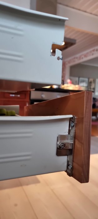 Närbild av en öppen låda med metalliskt lådbeslag fäst vid lådkanten och skåpets insida.