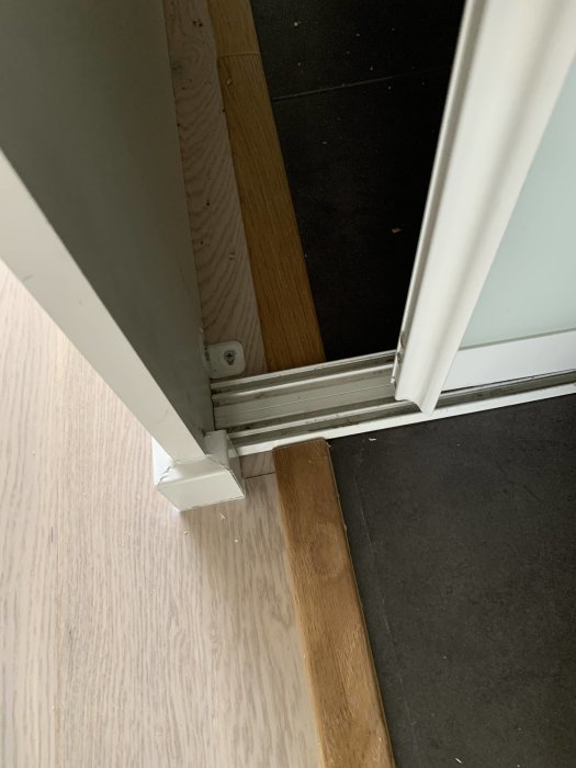 Ojämn installation av två olika golvlister vid en dörrtröskel, en under garderoben i två delar och den andra smal och hög.