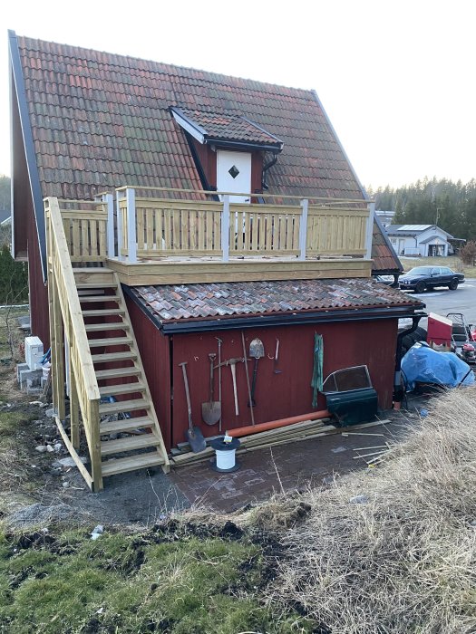 Hus med nybyggt bodtak och träveranda, verktyg på väggen, och kvarvarande snea takpannor.